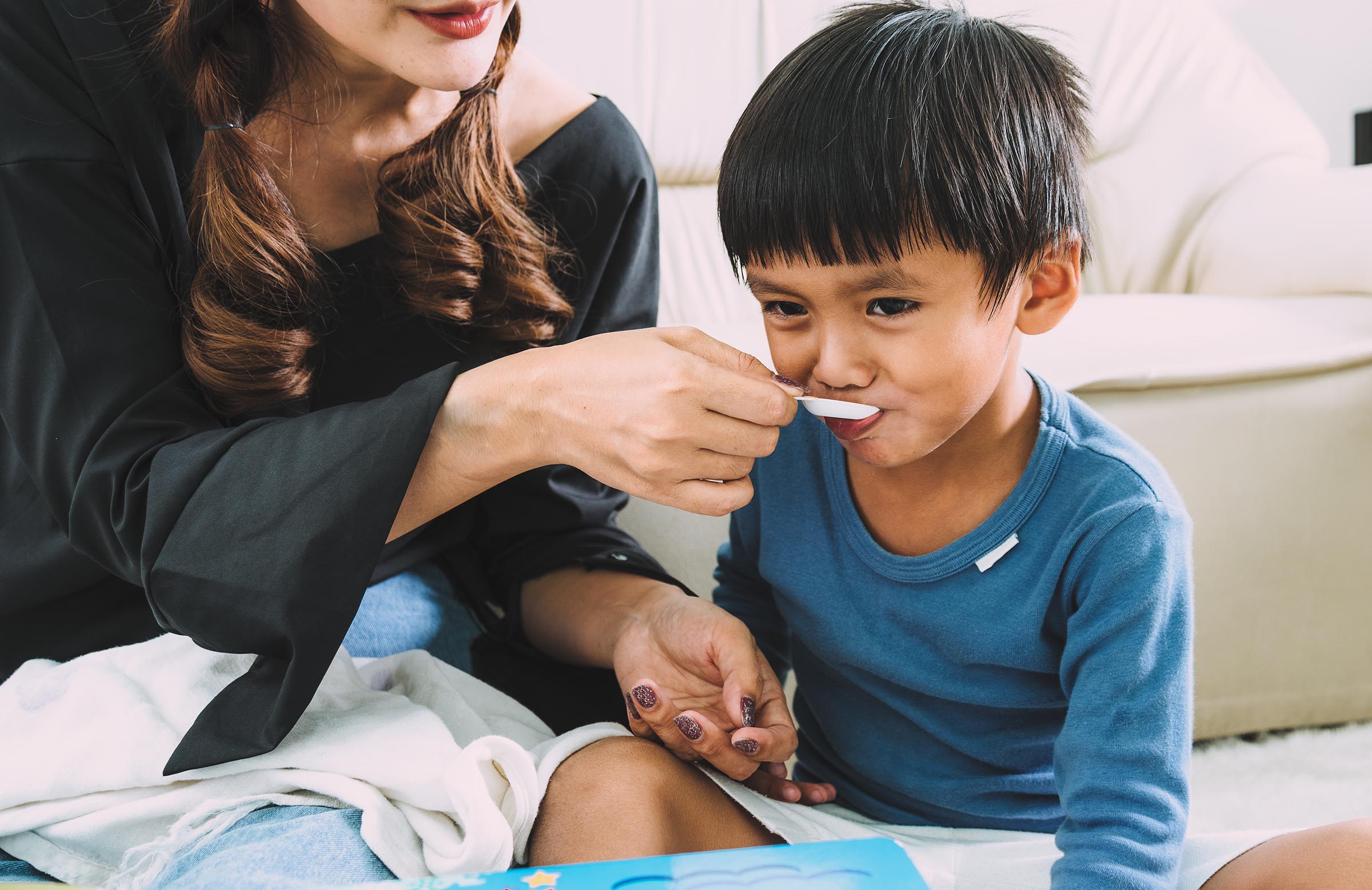 Mother giving her son medication from a spoon