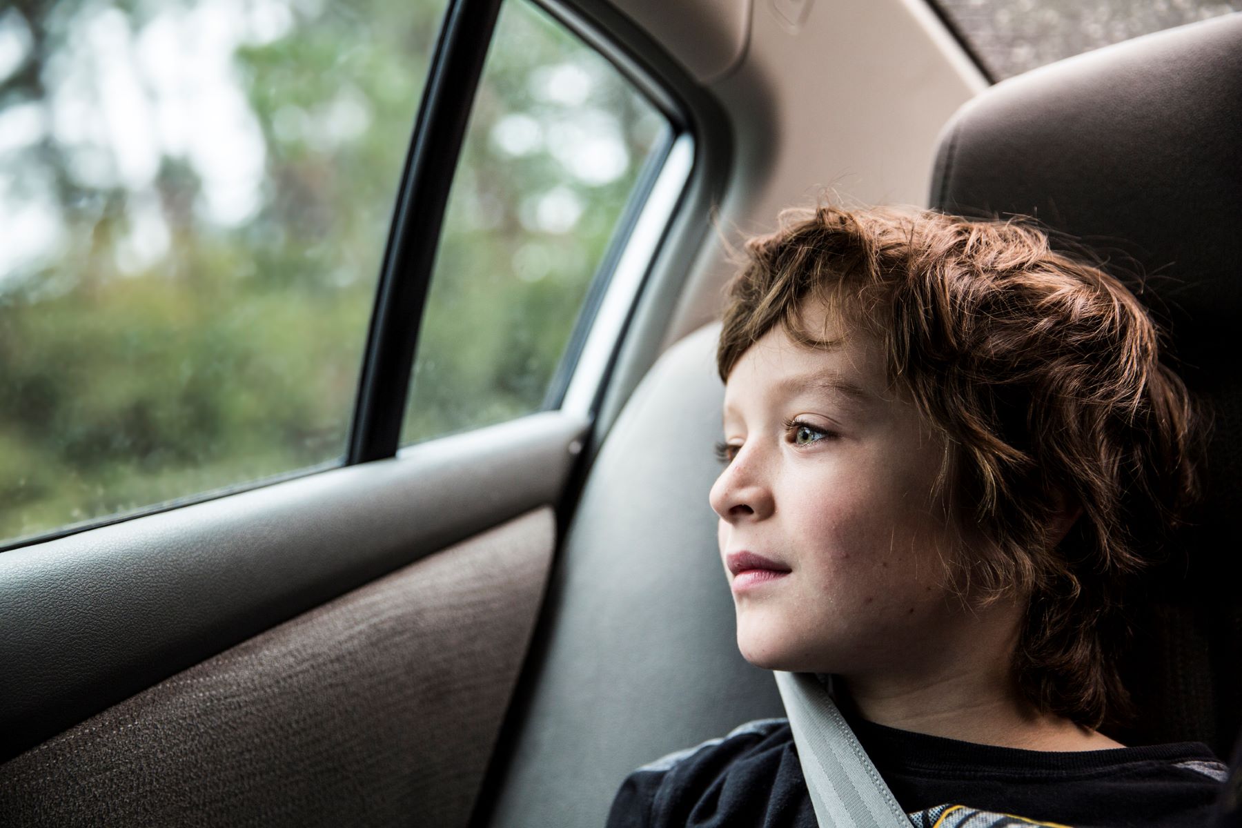 boy staring out of a car window