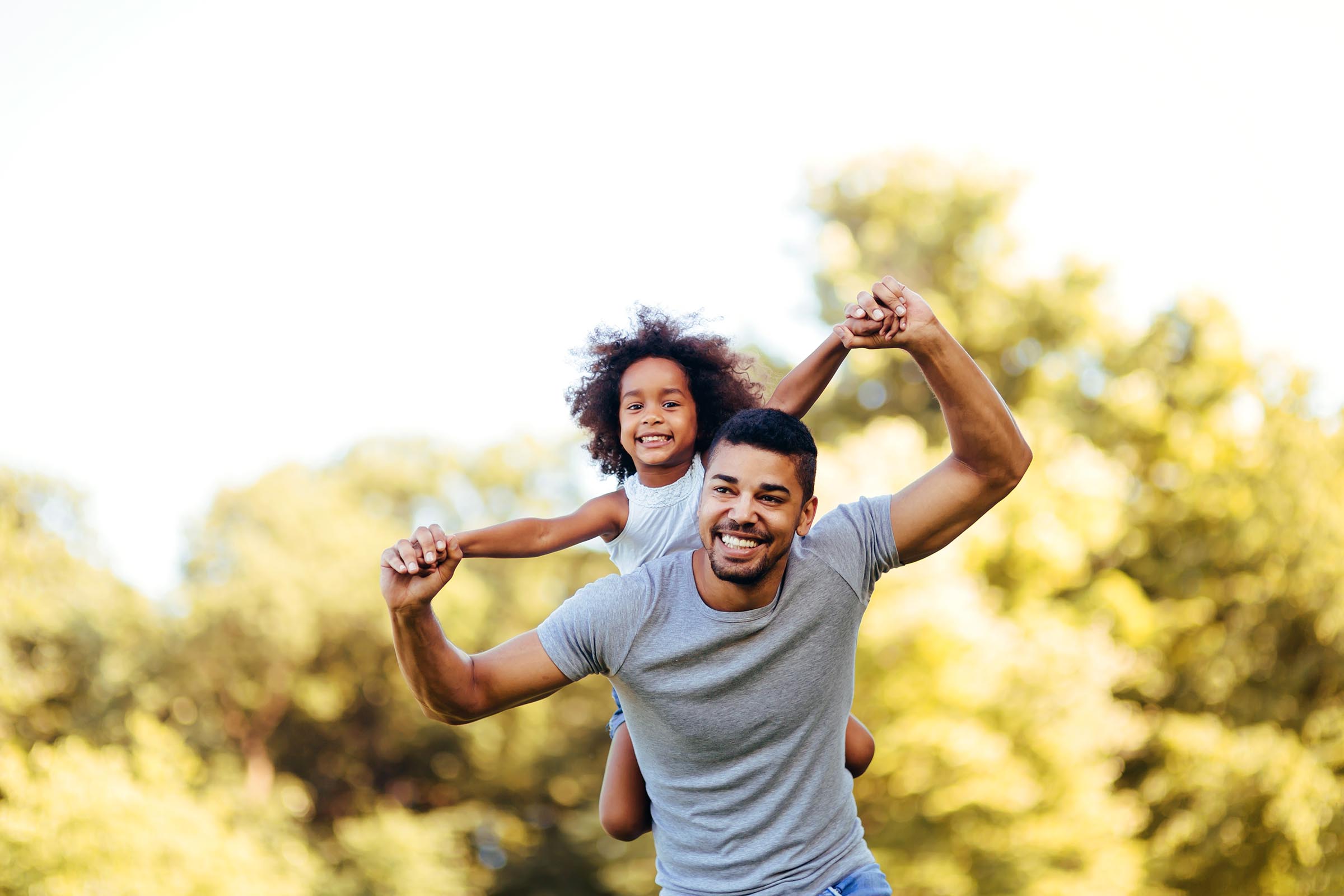 father with smiling girl on his shoulders