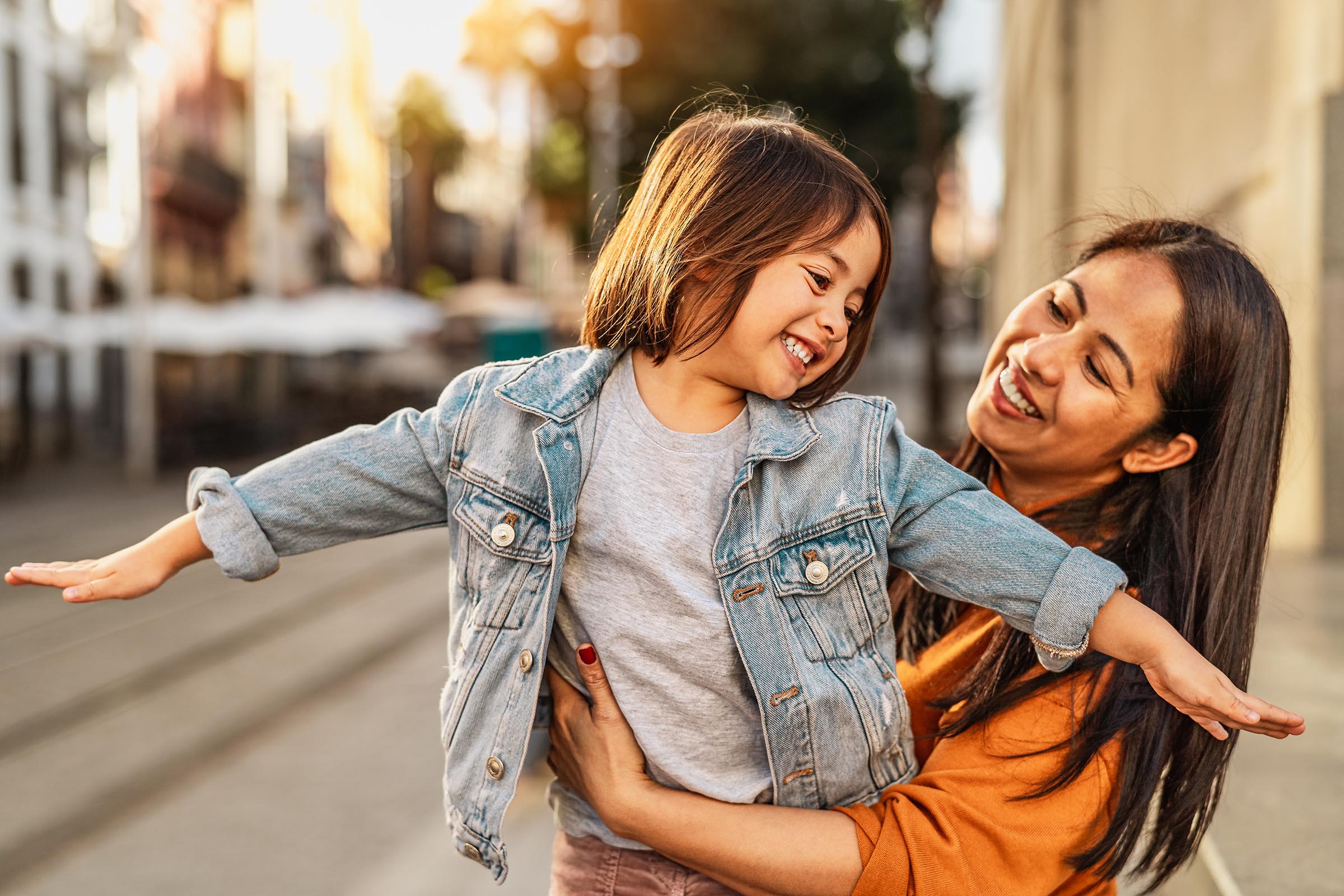 girl playing airplane in her mother's arms